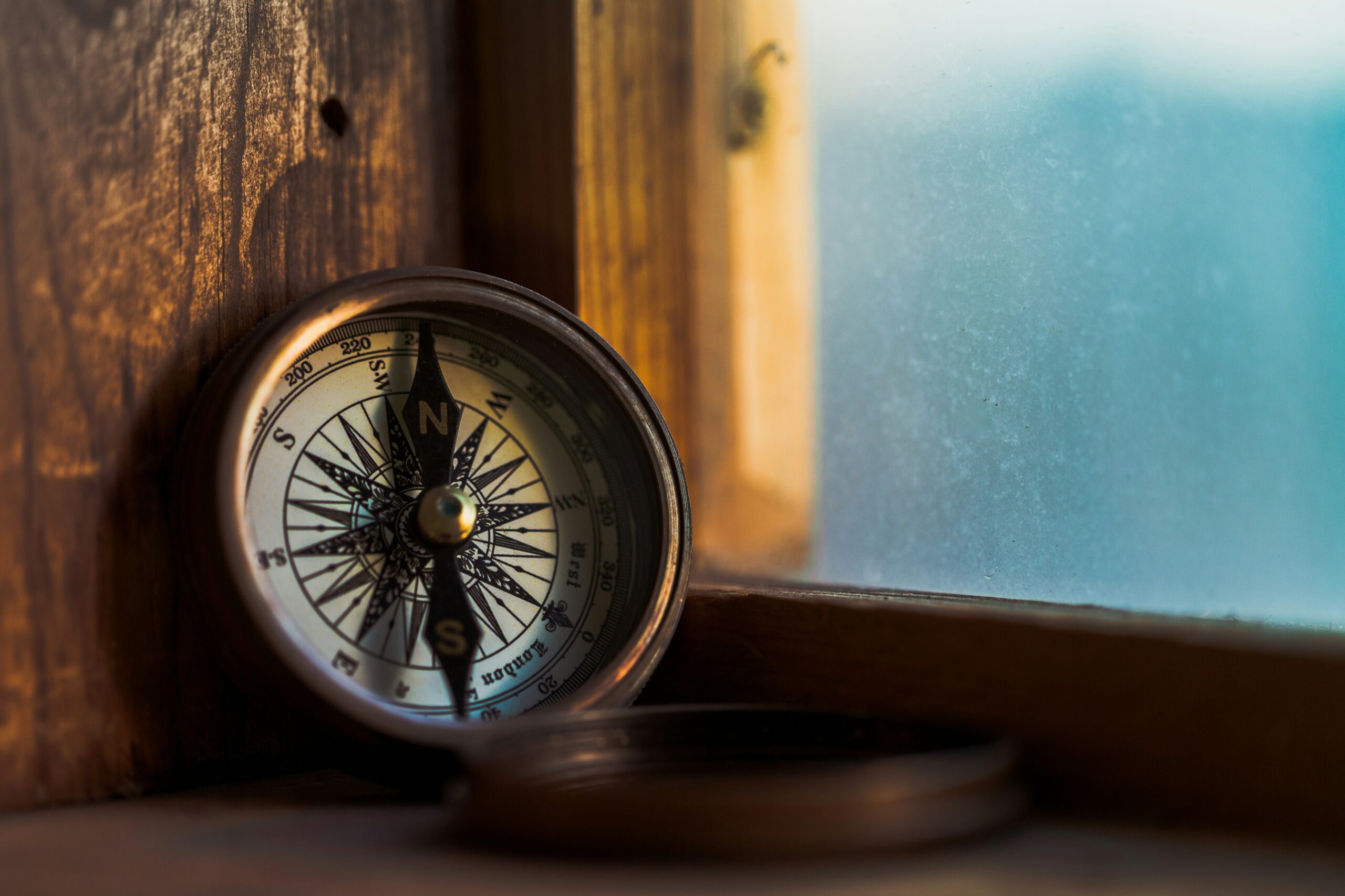 A compass pointing true north on a wooden window ledge.