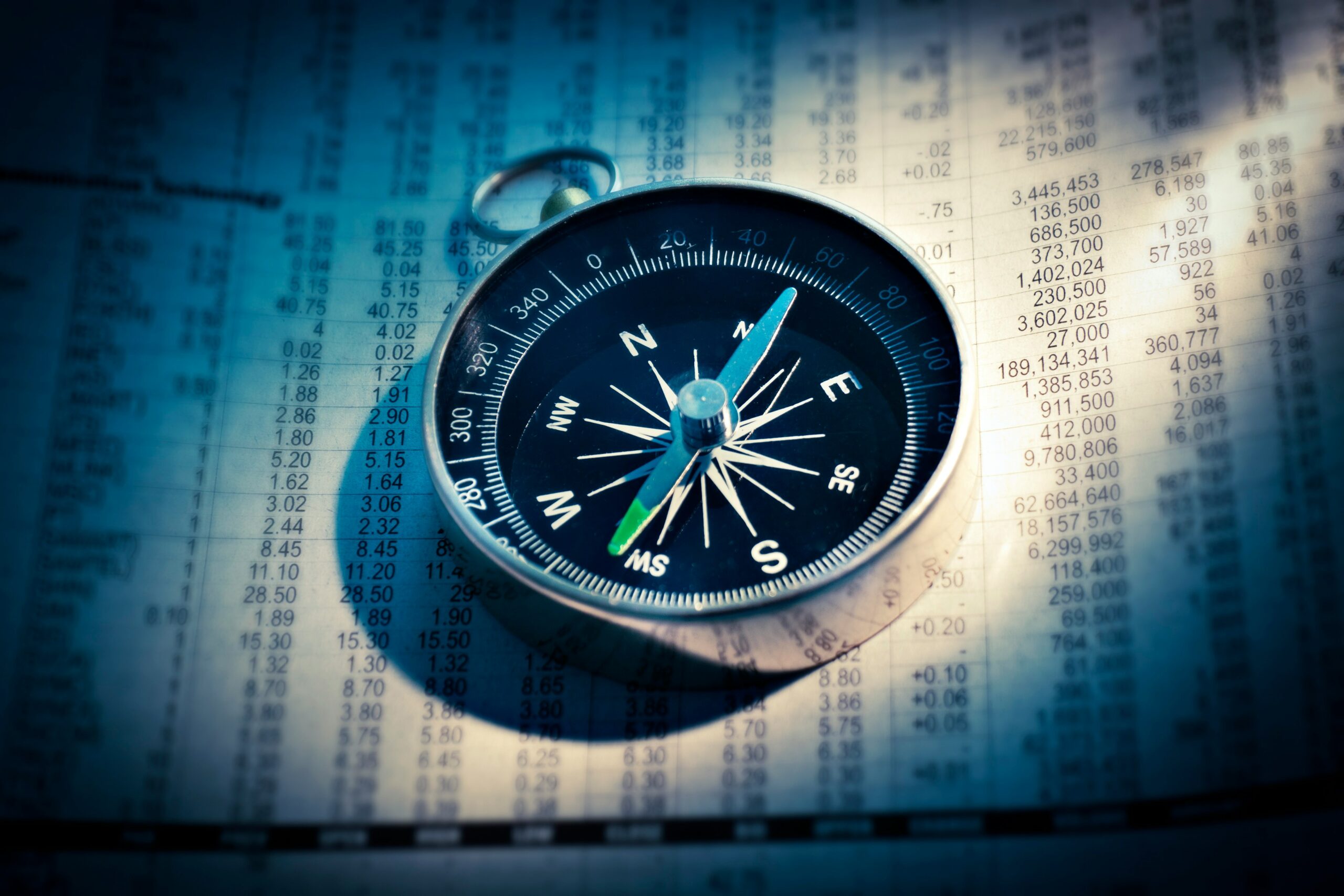 photo of a compass on a spreadsheet with data.